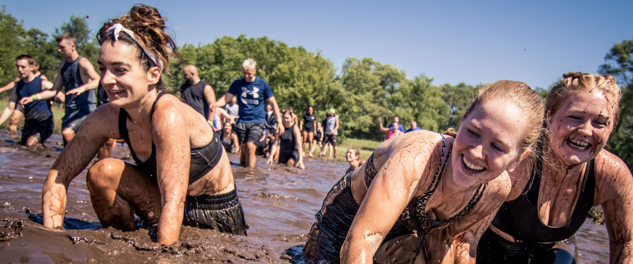 Participants crawling through the mud