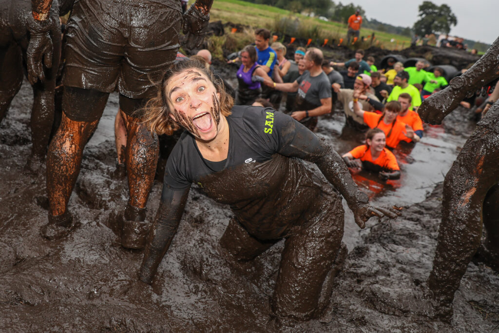 Participant smiling for the photo while covered with mud