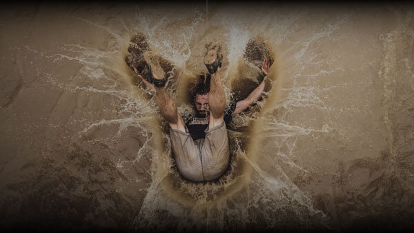 Tough Mudder Participant falling backwards into muddy water
